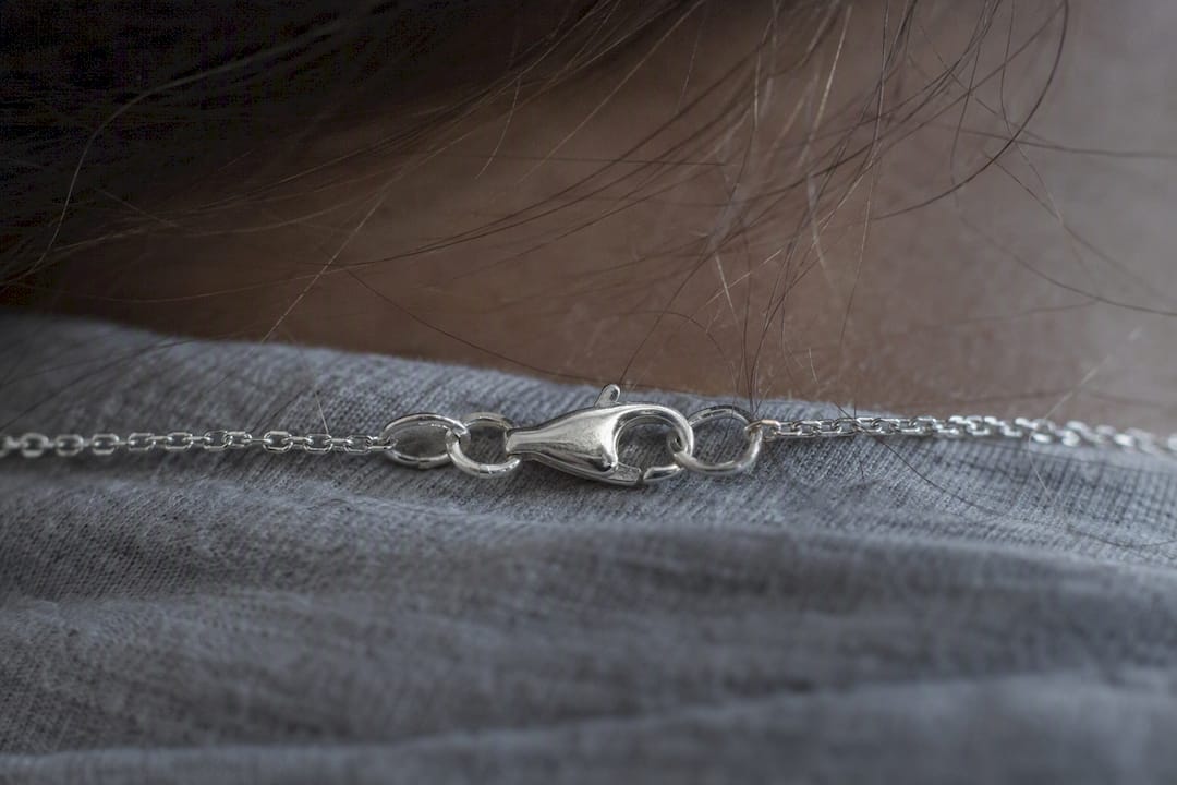 Close-up of silver chain clasp near hair strands