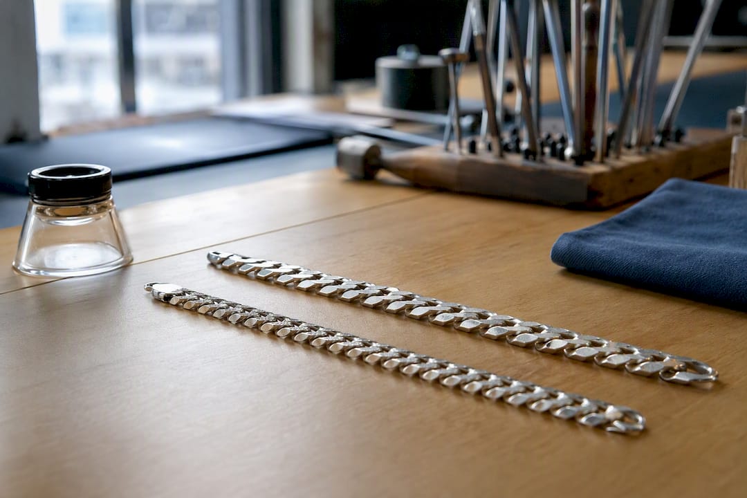 Close-up of silver curb and Cuban chains side by side