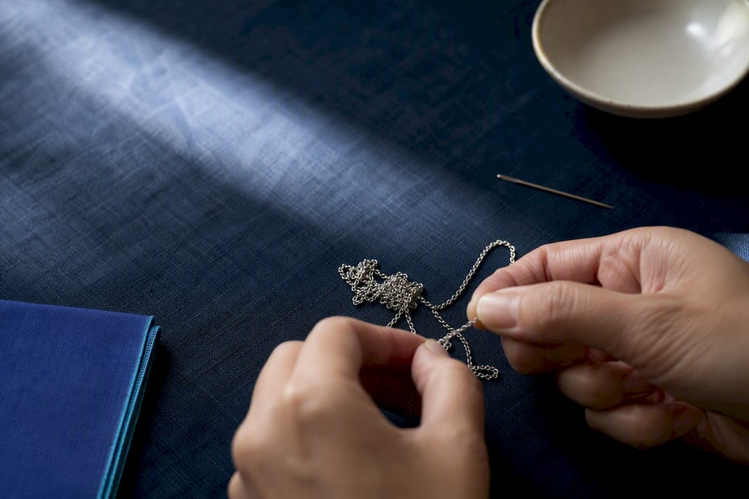 Hands loosening a tangled necklace at home