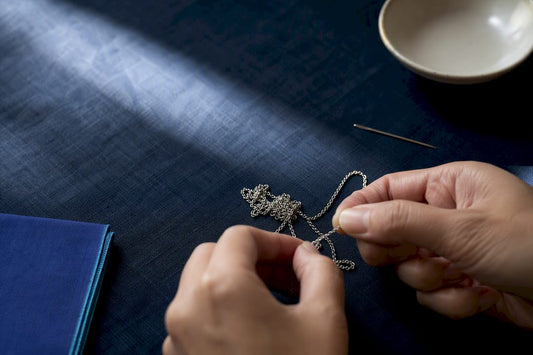 Hands loosening a tangled necklace at home