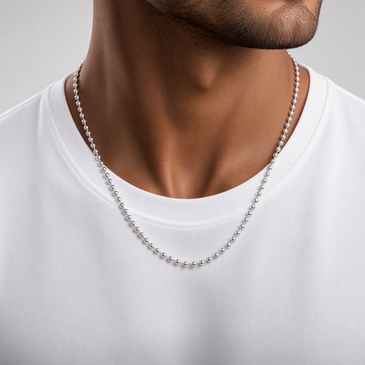 A close-up of a man's neck and chest wearing a silver ball chain necklace over a white t-shirt.