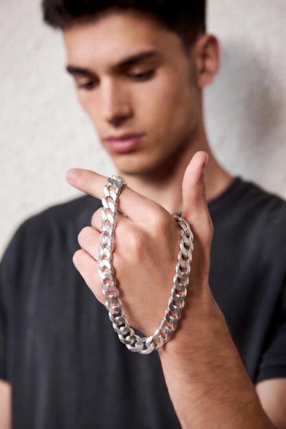 Man wearing a silver chain bracelet on a plain background