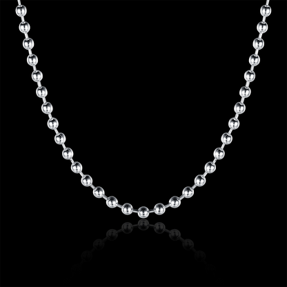 A silver ball chain necklace with polished metallic spherical links, displayed in a U-shape against a solid black background with a subtle reflection below.