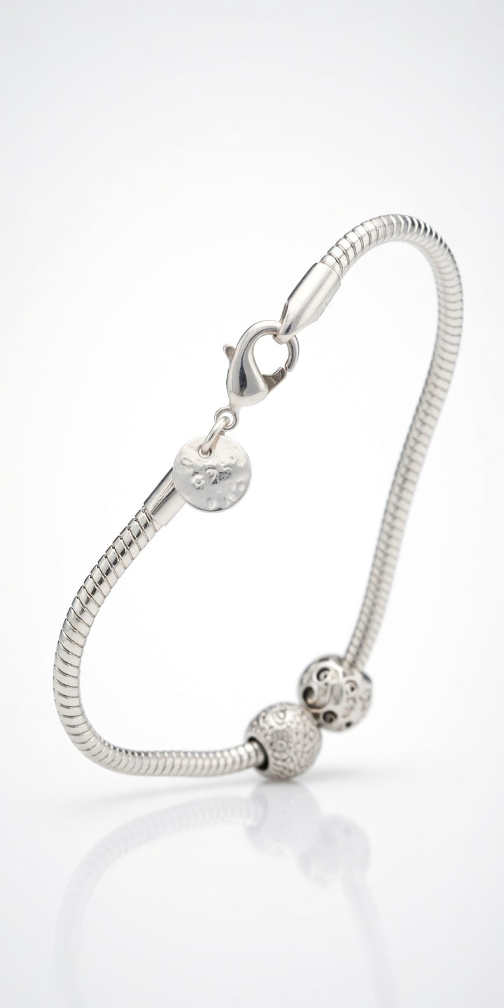 Silver bracelet with heart and round charm on a white background