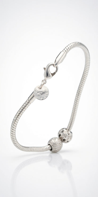 Silver bracelet with heart and round charm on a white background